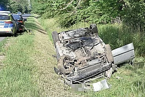 Leżące na dachu auto - wewnątrz zakleszczony, ranny mężczyzna